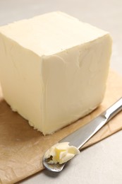 Block of tasty butter and knife on light table, closeup