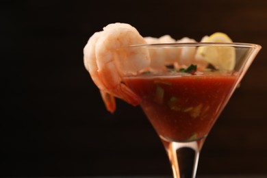 Tasty shrimp cocktail with sauce in glass on dark background, closeup. Space for text