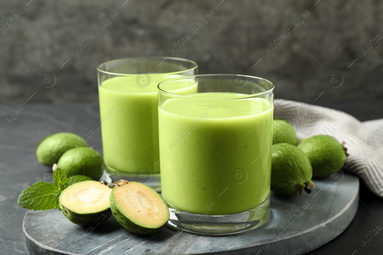 Photo of Fresh feijoa smoothie and fresh fruits on grey board, closeup