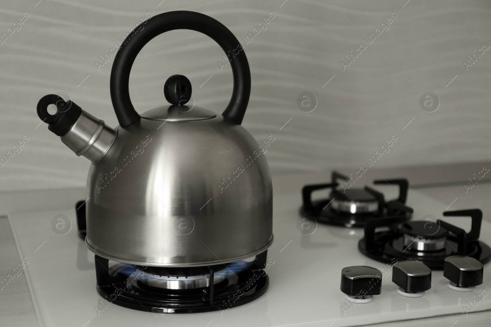 Photo of Steel kettle with whistle on modern gas stove. Space for text