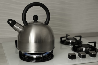 Photo of Steel kettle with whistle on modern gas stove. Space for text