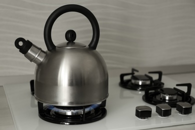 Steel kettle with whistle on modern gas stove. Space for text