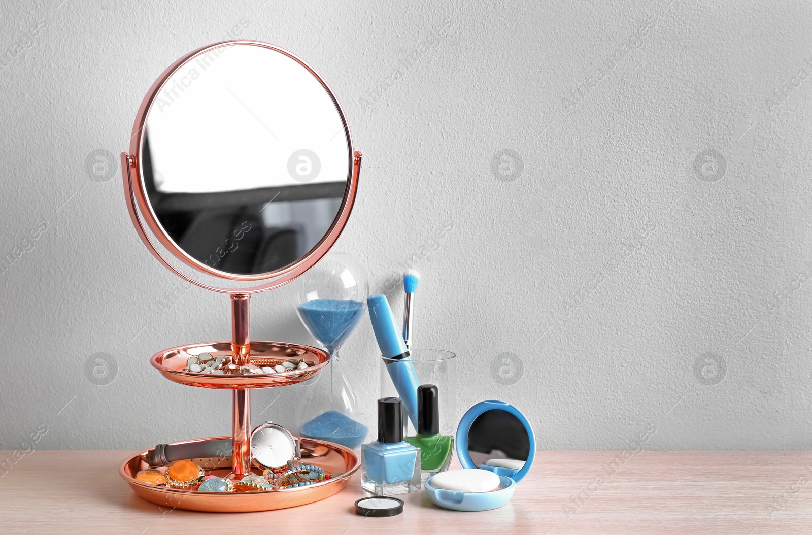 Photo of Modern mirror with makeup products and accessories on table near color wall