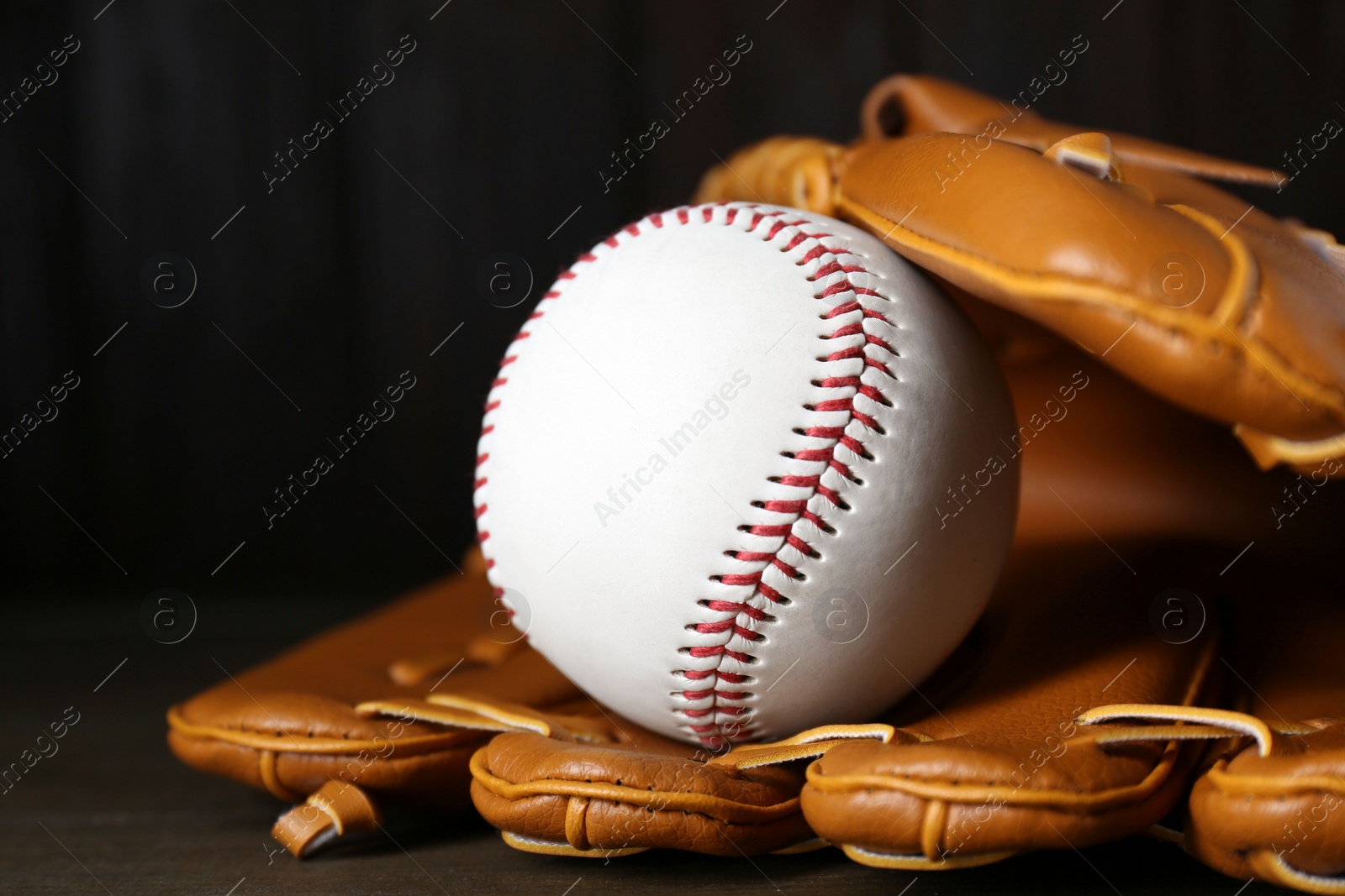 Photo of Leather baseball glove with ball on wooden table, closeup