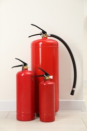 Photo of Fire extinguishers on floor near light wall indoors