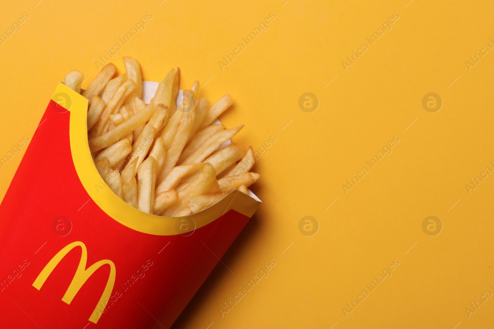 Photo of MYKOLAIV, UKRAINE - AUGUST 12, 2021: Big portion of McDonald's French fries on orange background, top view. Space for text