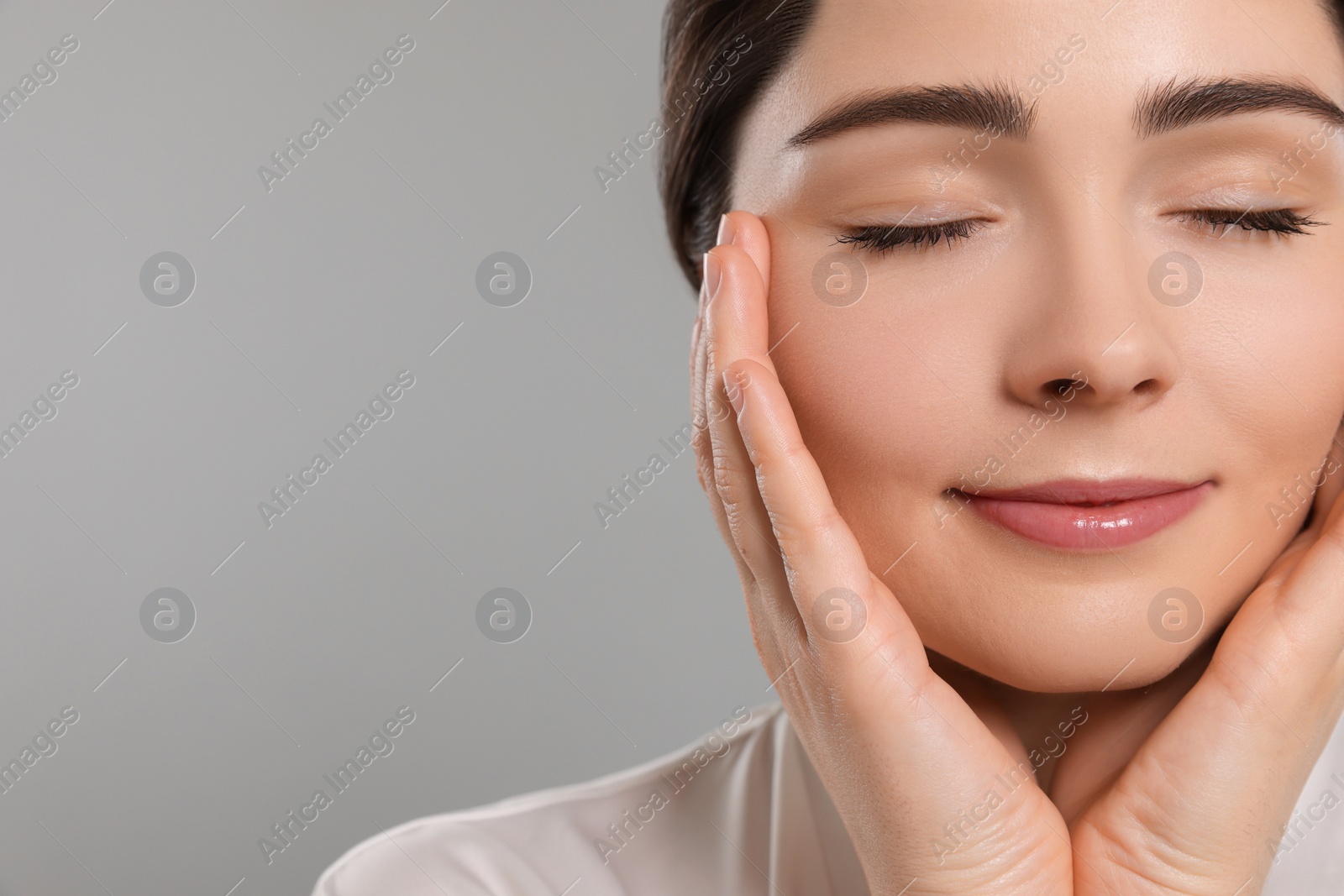 Photo of Young woman massaging her face on grey background. Space for text