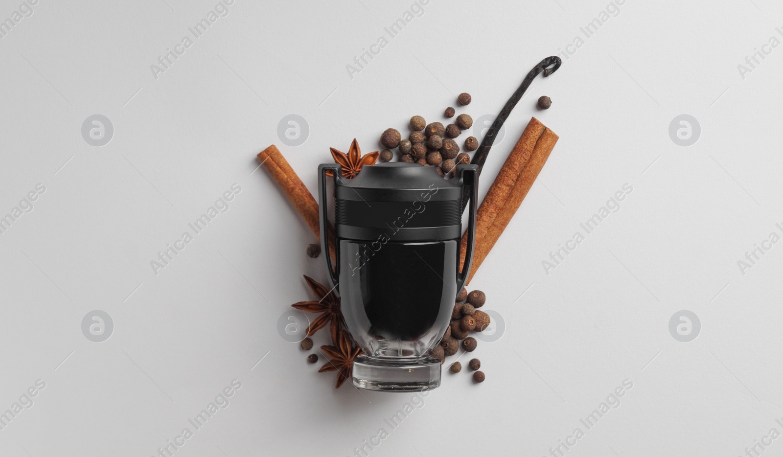 Photo of Bottle of perfume surrounded by different spices on white background, top view