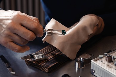 Photo of Professional jeweler working with gemstone at table, closeup