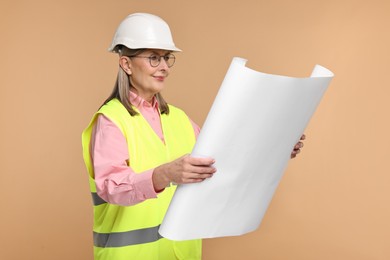 Photo of Architect in hard hat with draft on beige background