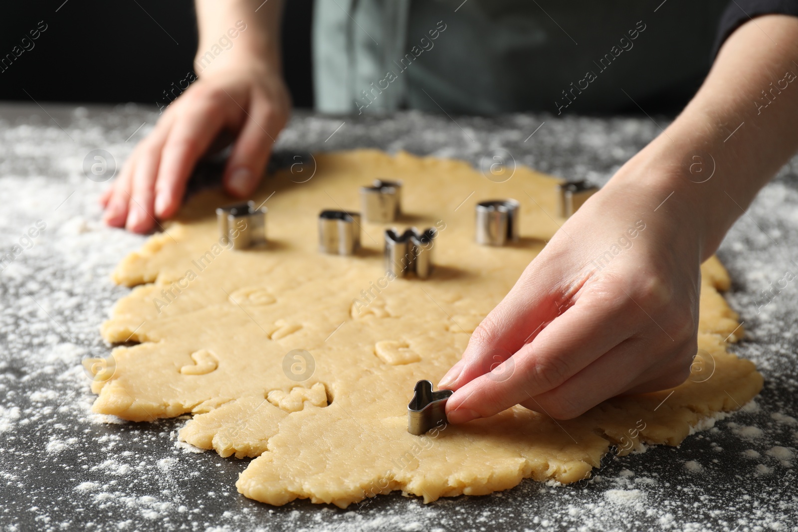 Photo of Shortcrust pastry. Woman making cookies with cutter at grey table, closeup