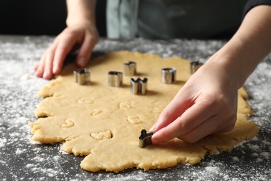Photo of Shortcrust pastry. Woman making cookies with cutter at grey table, closeup