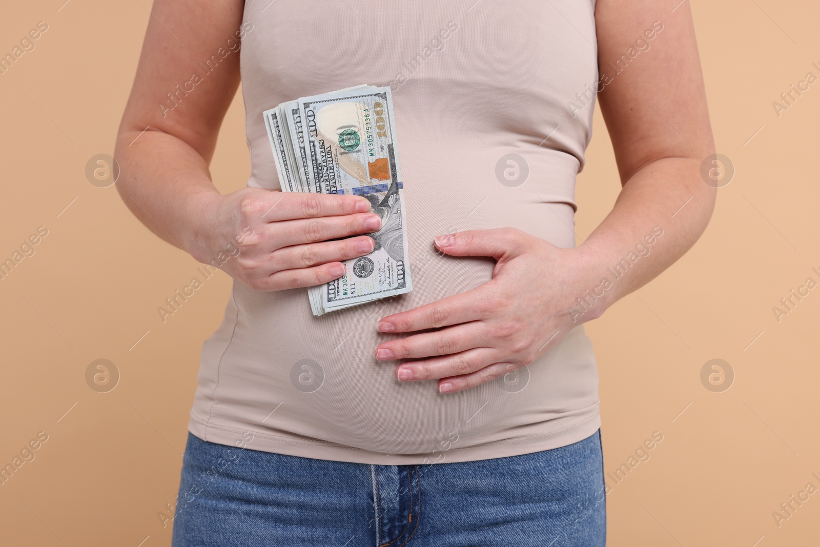 Photo of Surrogate mother. Pregnant woman with dollar banknotes on beige background, closeup