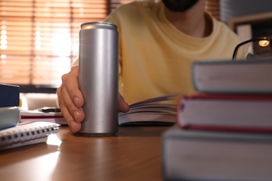 Photo of Young man with energy drink studying at home, closeup