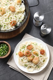 Photo of Delicious scallop pasta with green onion served on grey table, flat lay