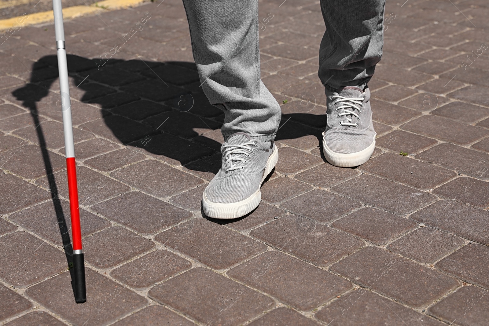 Photo of Blind person with cane walking outdoors, closeup