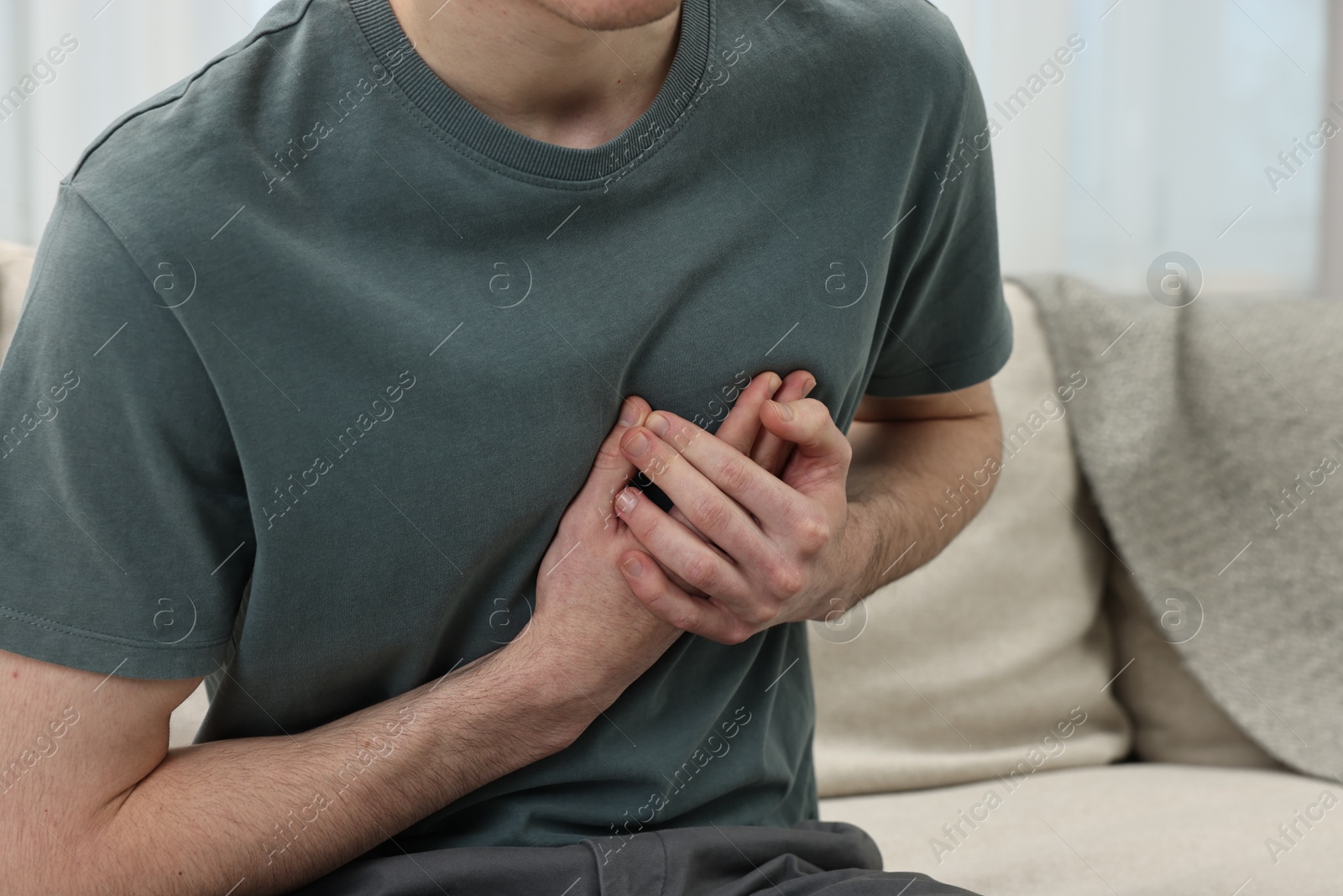 Photo of Man suffering from heart hurt on sofa at home, closeup