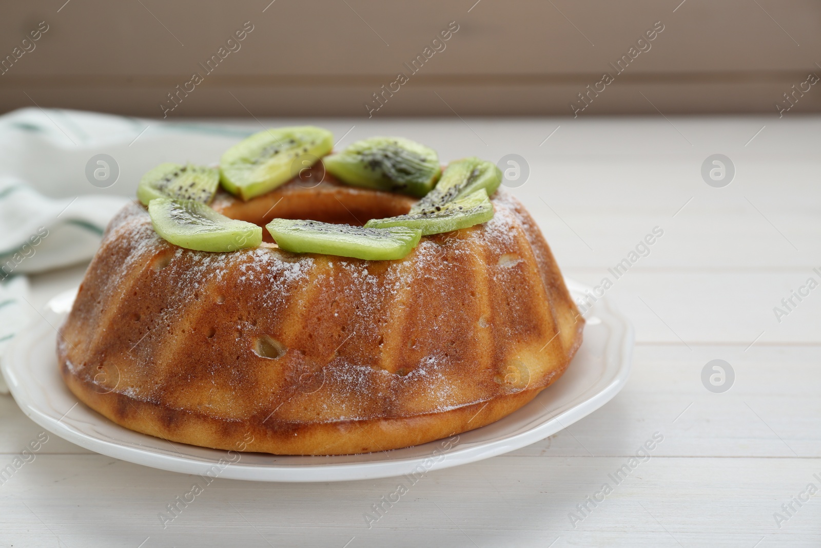 Photo of Homemade yogurt cake with kiwi and powdered sugar on white wooden table