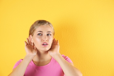Photo of Young woman with hearing problem on color background. Copy space text