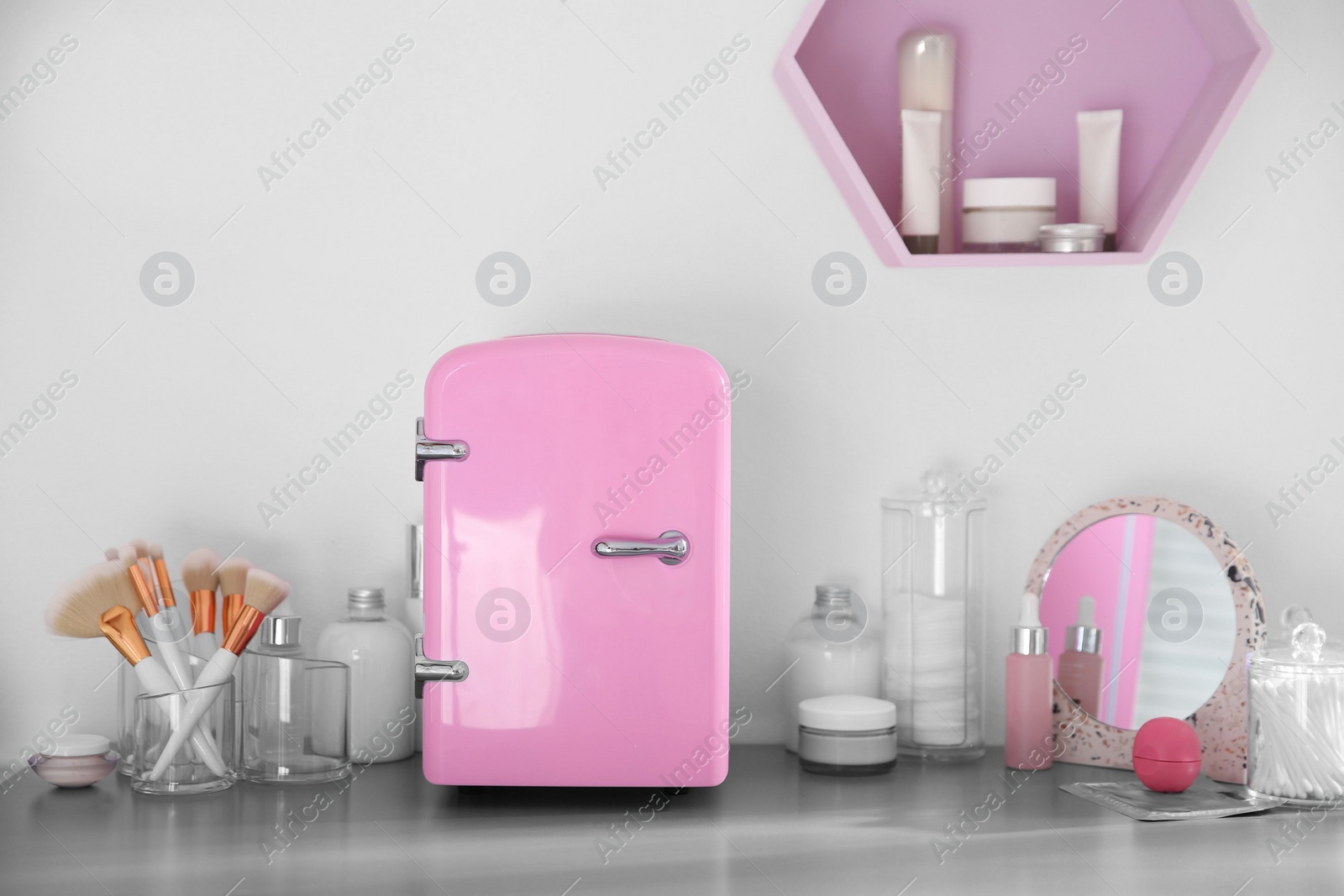 Photo of Cosmetics refrigerator and skin care products on grey vanity table indoors