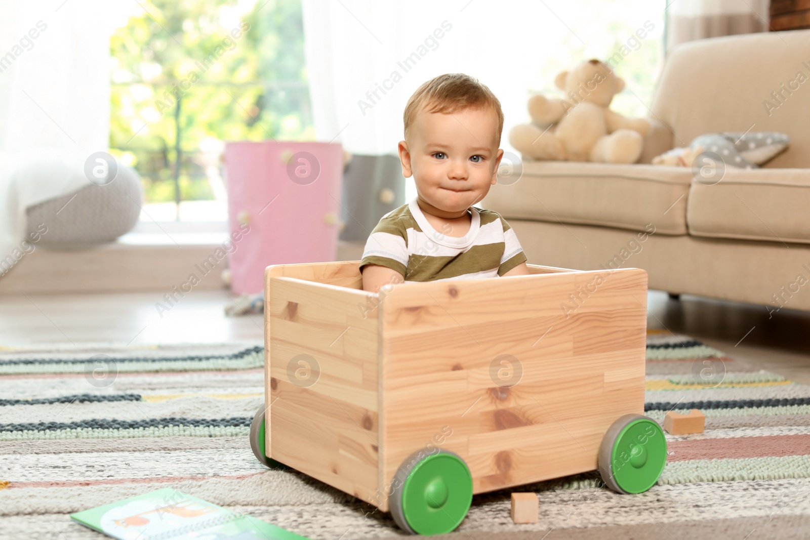 Photo of Adorable little baby in wooden cart at home