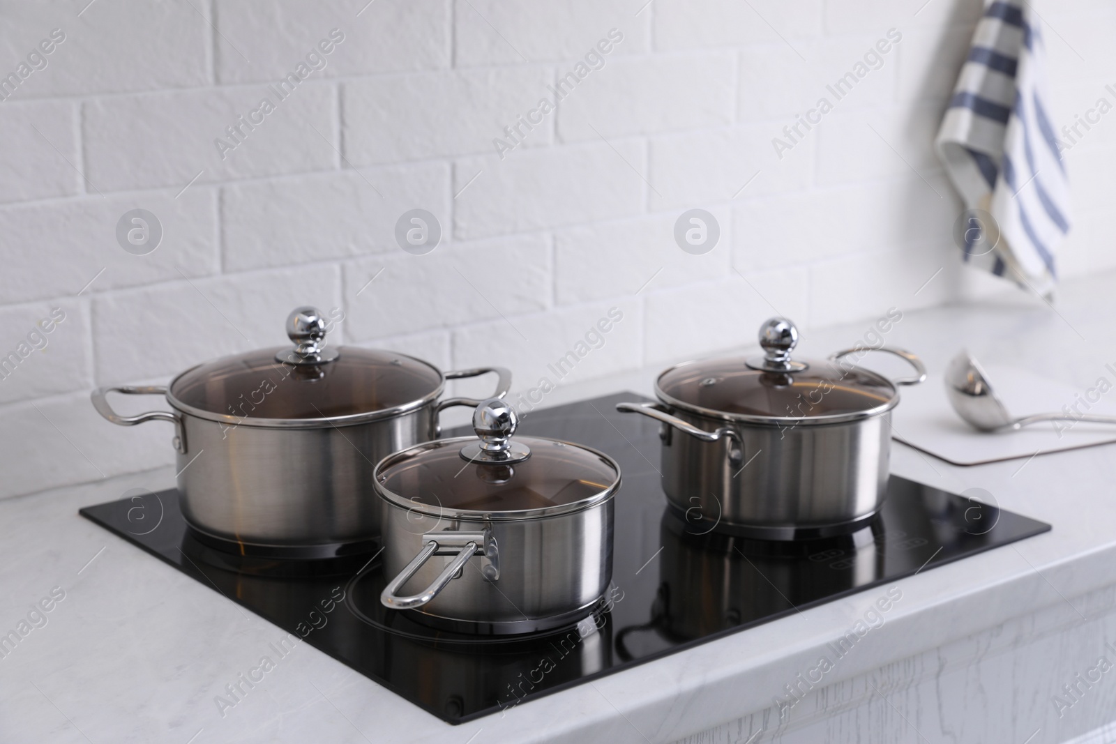 Photo of Set of new clean cookware on cooktop in kitchen