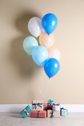 Photo of Many gift boxes and balloons near beige wall