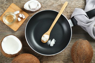 Flat lay composition with frying pan and organic coconut cooking oil on wooden table