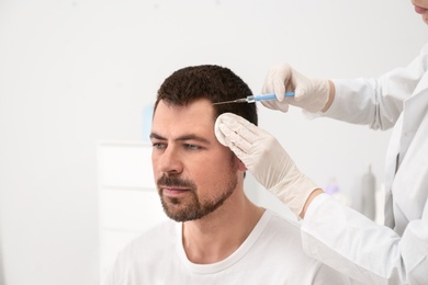 Photo of Man with hair loss problem receiving injection in salon