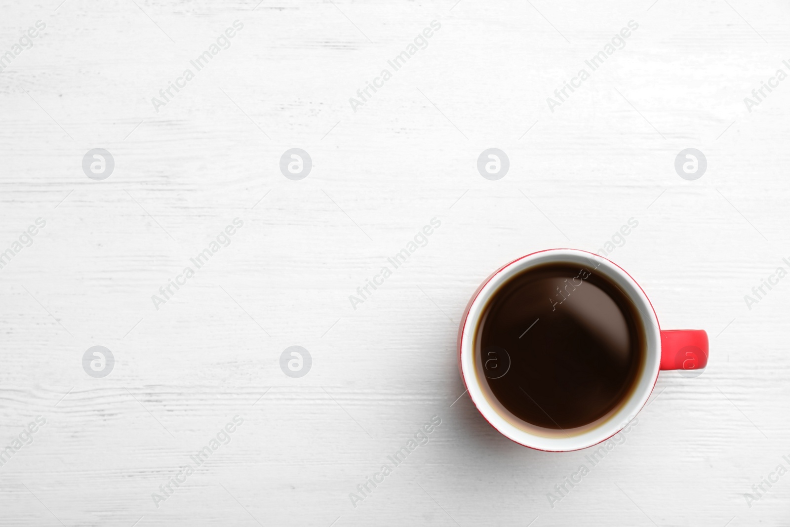 Photo of Ceramic cup with hot aromatic coffee on wooden background, top view