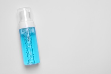 Photo of Bottle of face cleansing product on white background, top view. Space for text