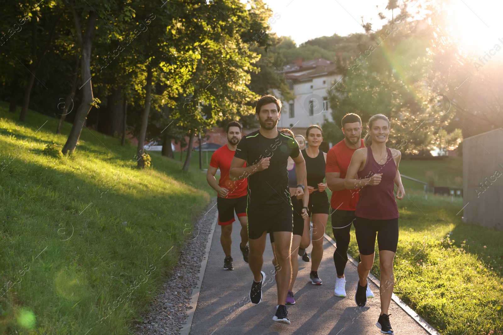 Photo of Group of people running outdoors on sunny day. Space for text