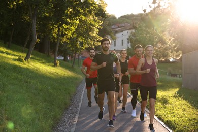 Group of people running outdoors on sunny day. Space for text