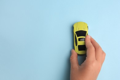 Photo of Child playing with toy car on light blue background, top view. Space for text