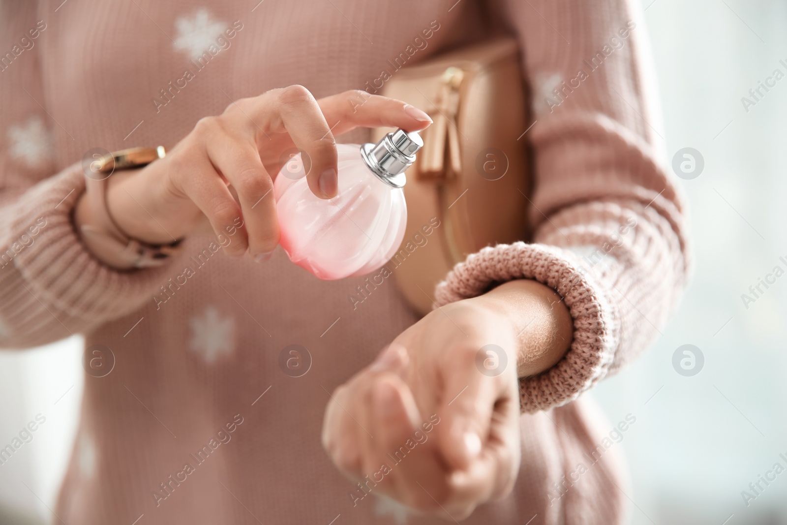 Photo of Young woman using perfume indoors, closeup