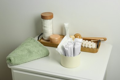 Photo of Different feminine and personal care products on white nightstand near white wall