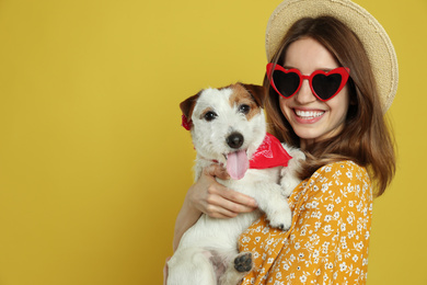 Photo of Young woman with her cute Jack Russell Terrier on yellow background, space for text. Lovely pet