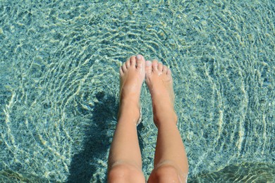 Photo of Child holding feet on surface of water in sea, closeup