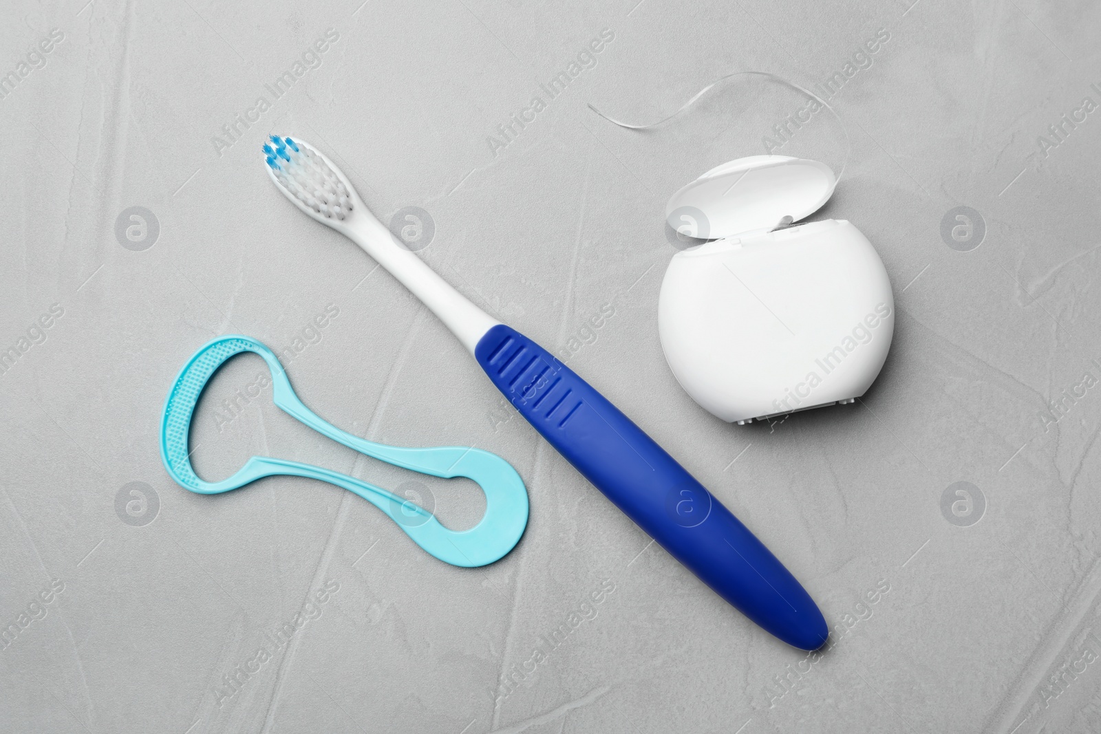 Photo of Tongue cleaner, dental floss and toothbrush on grey background, flat lay