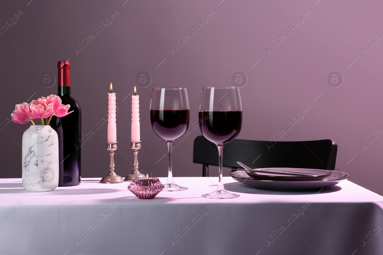 Photo of Romantic table setting with glasses of red wine and candles indoors