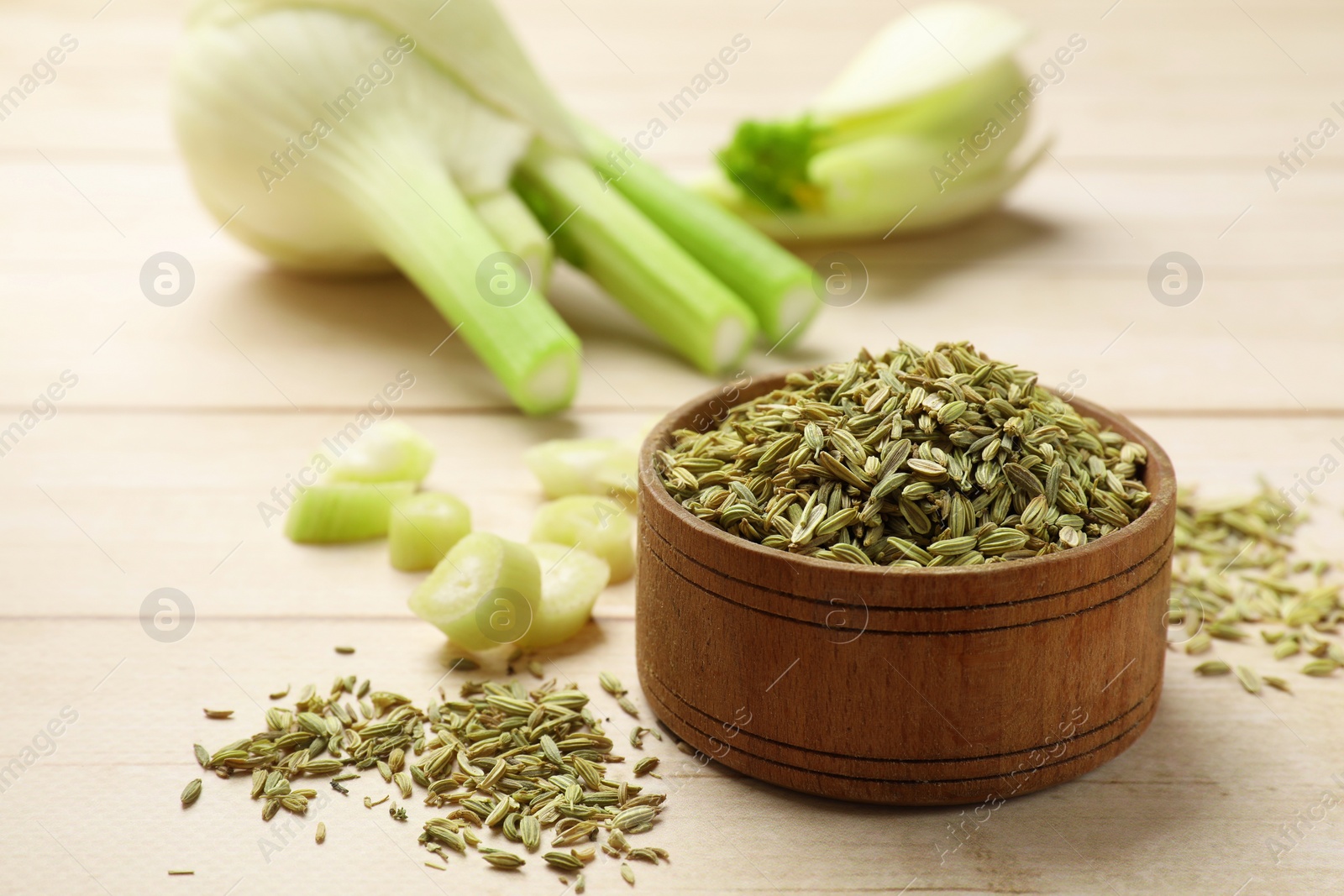 Photo of Bowl with dry fennel seeds on wooden table, space for text