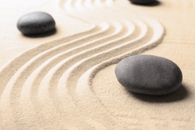 Photo of Zen garden stones on sand with pattern. Meditation and harmony