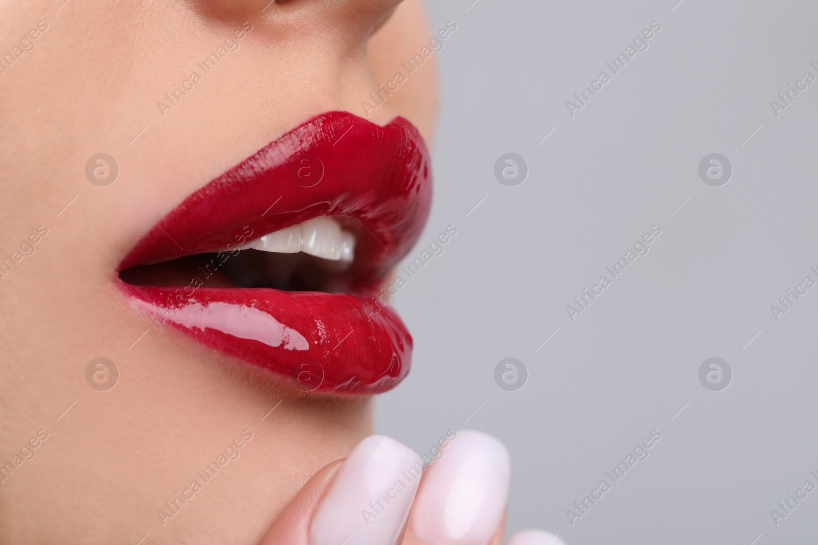 Photo of Closeup view of beautiful young woman with perfect lips makeup on light grey background. Space for text