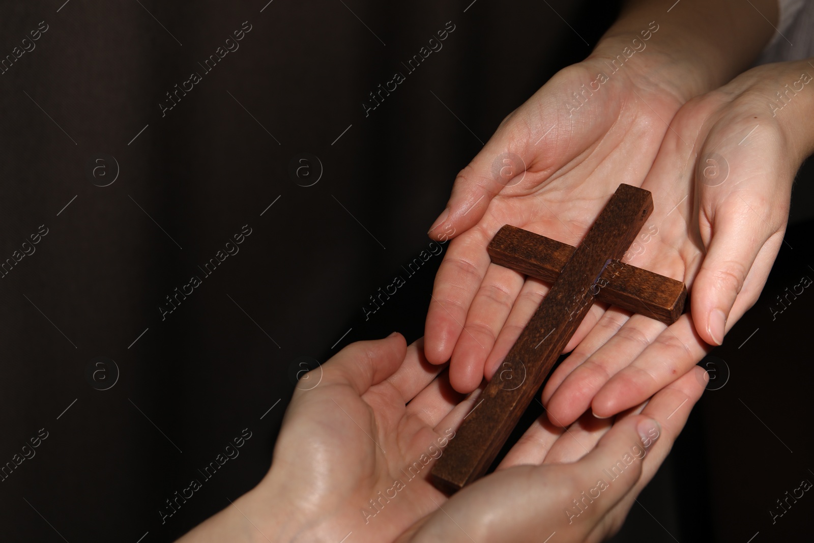 Photo of Easter - celebration of Jesus resurrection. Women holding wooden cross on dark background, closeup. Space for text