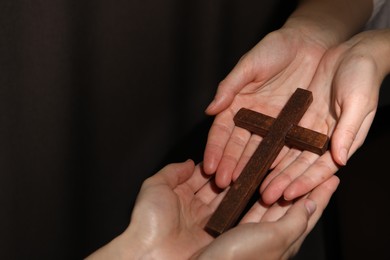 Photo of Easter - celebration of Jesus resurrection. Women holding wooden cross on dark background, closeup. Space for text