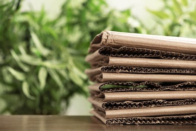 Stack of cardboard for recycling on table against blurred background. Space for text