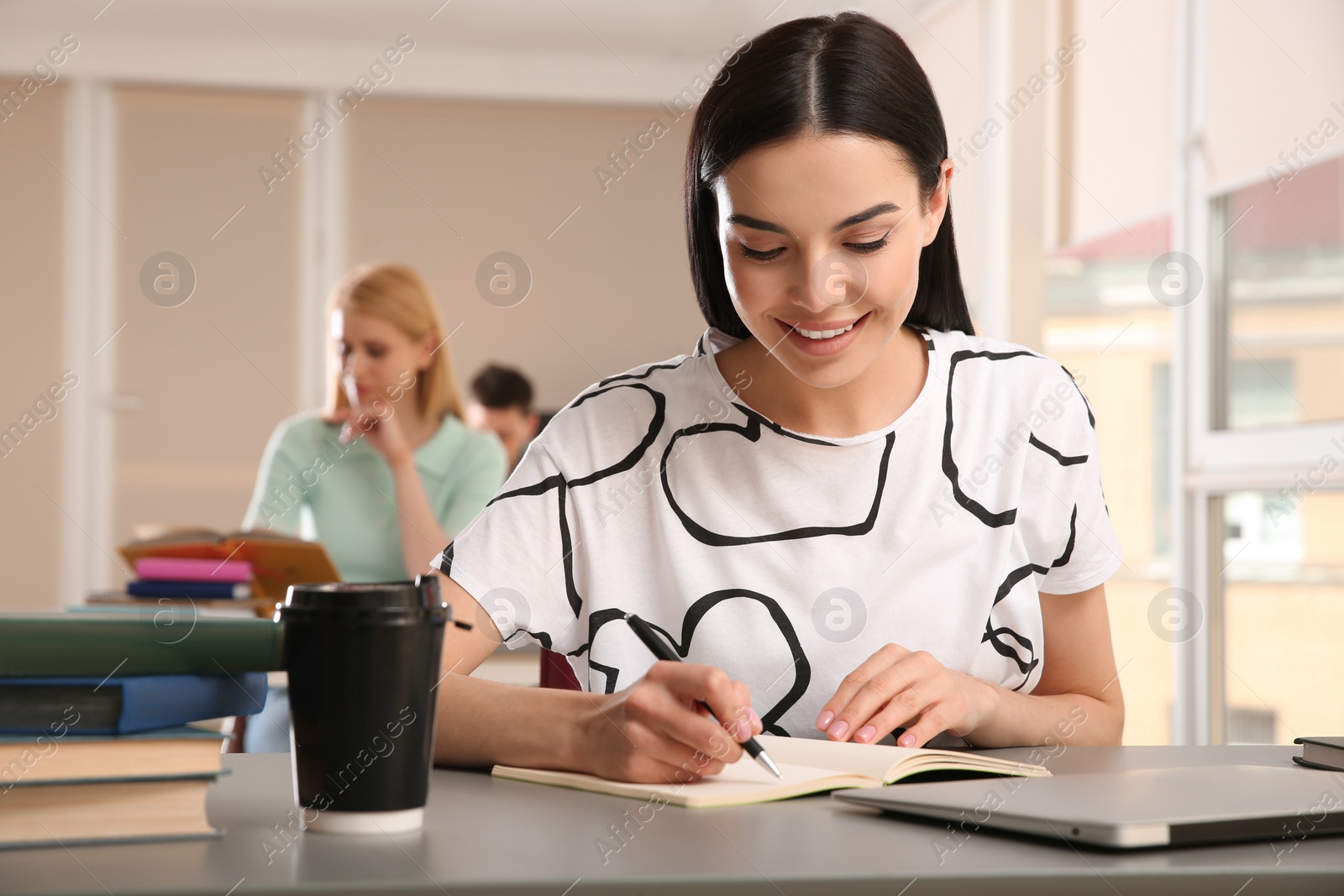 Photo of Young woman studying at table in library