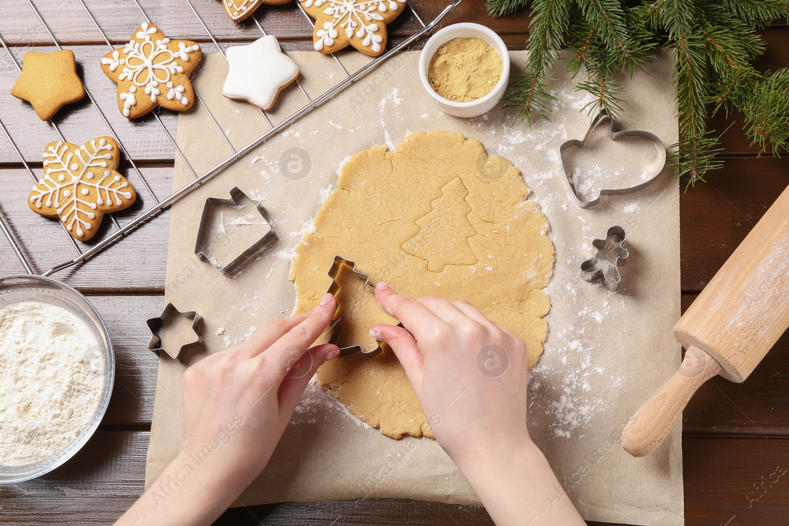 Photo of Woman making Christmas cookies with cutters at wooden table, top view