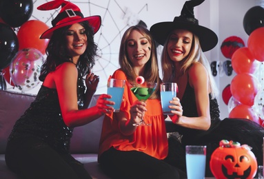 Photo of Group of friends toasting with cocktails at Halloween party indoors