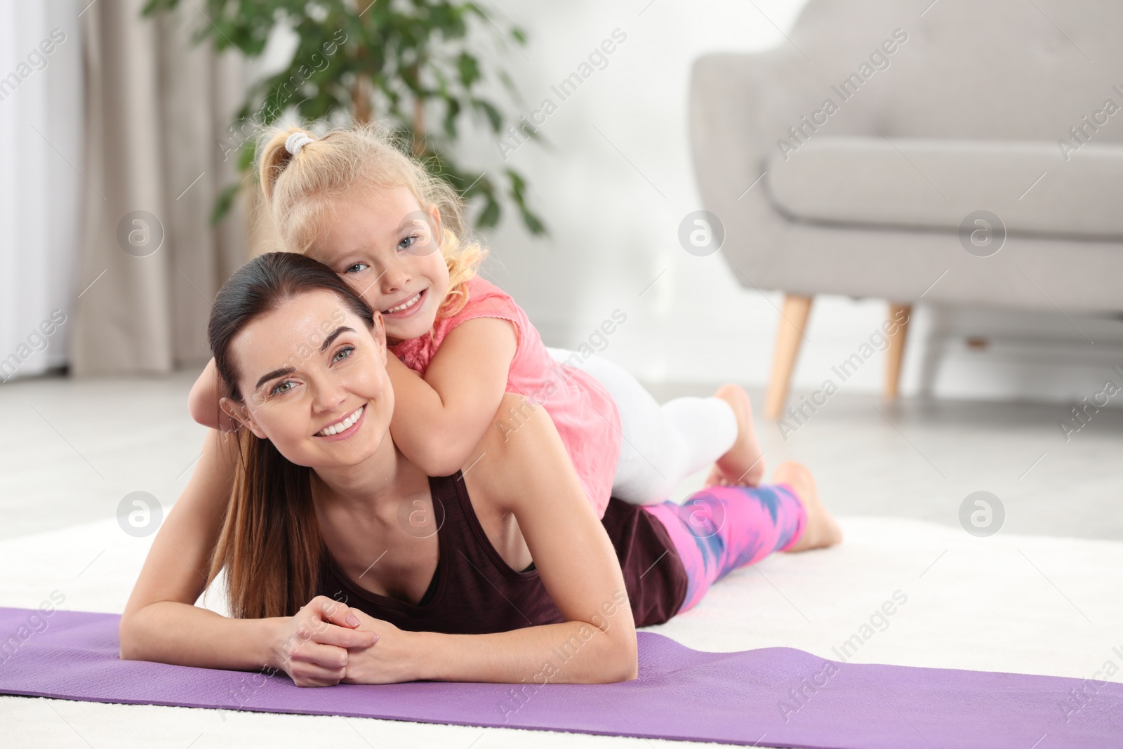 Photo of Woman with daughter lying on fitness mat at home. Space for text